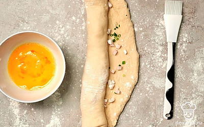 Приготовьте багет со свиным салом. Готовое тесто раскатайте в прямоугольный пласт. Выложите равномерно начинку. Сверните в рулет, не забыв подвернуть края. Сверху сделайте зигзагообразные надрезы. Смажьте сверху яйцом. Запекайте при 180 градусах 30-40 минут.