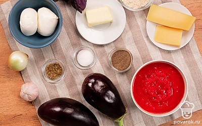 Удобно расположите нужные ингредиенты. Баклажаны помойте и нарежьте кольцами толщиной не более сантиметра. Выложите их на бумажное полотенце и накройте чем-то тяжелым, оставьте на 30 минут. Это нужно, чтобы из баклажанов ушла влага. Сыр моцарелла также нарежьте кольцами. Твердый сыр натрите на терке. Чеснок и лук почистите, помойте и мелко нарежьте. Базилик помойте и обсушите бумажными полотенцами. Подготовьте духовку и столовые приборы.