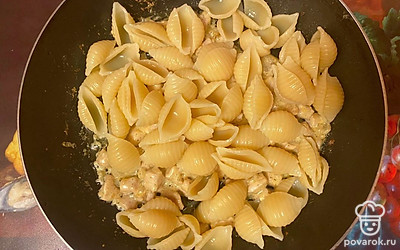 После этого выложите к ингредиентам макароны, перемешайте. Отправьте вновь на умеренный огонь. Перемешав, томите под крышкой в течение 12-14 минут. После этого опять перемешайте, выключите огонь, накройте крышкой и оставьте так на 10 минут.