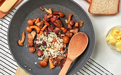 Подготовьте ингредиенты для начинки. Разогрейте на сильном огне сковороду, убавьте огонь и обжарьте нарезанный лук с небольшим количеством растительного масла. К луку добавьте грибы и протушите все вместе около 10-15 минут до готовности грибов.