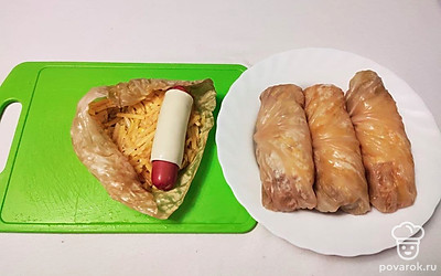 Положите тертый картофель на дуршлаг, так чтобы стек сок с него. Затем добавьте соль, перец и 1 яйцо. Каждую сосиску заверните в ломтик сыра. На лист капусты выложите 2 ст.л. картофеля, затем сосиску и заверните в виде рулета.