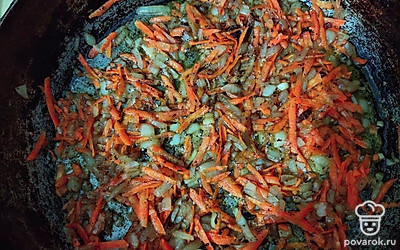 Закрученные сосиски обжарьте с каждой стороны на подсолнечном масле, а затем сложите в глубокий противень. Приготовьте сметанный соус. Для этого на ту же сковороду добавьте лук, морковь и немного обжарьте.