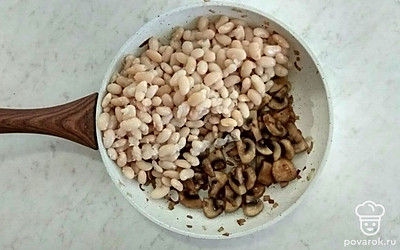 Когда лук станет прозрачным, добавьте грибы и обжаривайте на среднем огне примерно 3-5 минут, постоянно помешивая. Предварительно отварите фасоль. В сковороду с обжаренными ингредиентами добавьте фасоль.