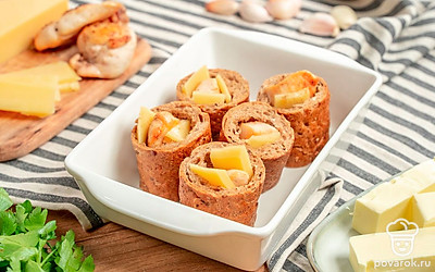 Подготовьте багет к запеканию. Порежьте багет на четыре кусочка. Из середины вырежьте мякиш. Куриное филе оберните сырным ломтиком. Вставьте внутрь багетных кусочков, выложите каждый на фольгу, сложенную в два раза.