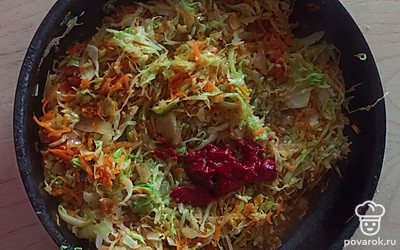 Добавить нашинкованную капусту и томатную пасту с водой. 