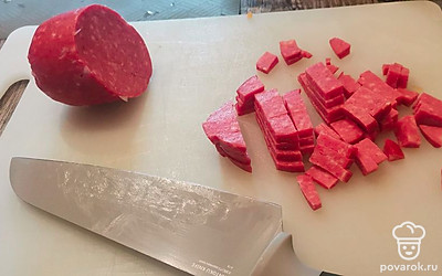 Нарежьте кубиками копченую колбасу.