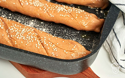 Приготовьте багеты с топленым маслом. Раскрутите тесто обратно в пласт. Снова смажьте маслом, скрутите в рулет. Краешек защипните. Выложите на противень швом вниз. Присыпьте сверху мукой. Смажьте желтком, посыпьте кунжутом. Сделайте надрезы поперек или по диагонали. Накройте полотенцем, оставьте на 40 минут для расстойки. После чего запеките при 200 градусах 30-35 минут.