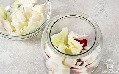 В контейнер для маринования выложите слоями половину свеклы, капусты, колечек перца и пластинок чеснока. 