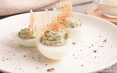 Переложите приготовленную смесь в яичные половинки. И красиво украсьте их приготовленной ажурной сетью.