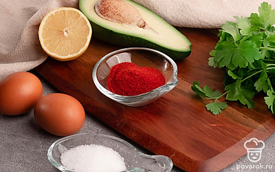 Приготовьте необходимые ингредиенты. Авокадо помойте и отрежьте половину. Яйца сварите. Лимон помойте и отрежьте половину. Зелень помойте и обсушите.