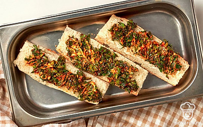 Приготовьте багет с сушеным чесноком. Багет разделите поперек на две части. Затем каждую из частей разрежьте вдоль. Нанесите на мякоть намазку. Выложите на противень. Подсушите в духовке при 180 градусах 10 минут.