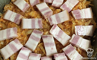 Разложите кусочки поверх капусты. Накройте крышкой и тушите пару минут, чтобы капуста с рисом пропитались грудинкой.