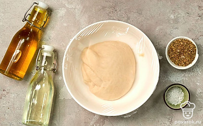 Приготовьте дрожжевое тесто. В отдельную емкость налейте воду, засыпьте сахар и сухие дрожжи. Мешайте до растворения сахара и дрожжей примерно 5 минут. Добавьте растительное масло и соль, перемешайте. Всыпайте муку небольшими порциями. Мешайте тесто ложкой или венчиком, после чего хорошо вымесите руками. Переложите тесто в отдельную емкость, смазанную растительным маслом. Закройте пищевой пленкой и уберите в теплое место на 60 минут.