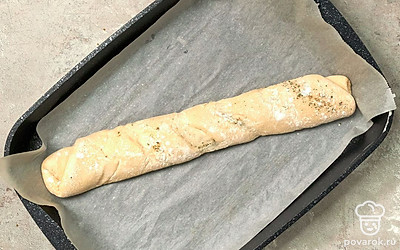 Испеките багеты. Переложите заготовку из теста в виде рулета на противень, застеленный пергаментной бумагой. Разогрейте духовой шкаф до 180 градусов, выпекайте багет в течение 30 минут до румяной корочки. Готовый багет переложите на решетку, сбрызните водой.