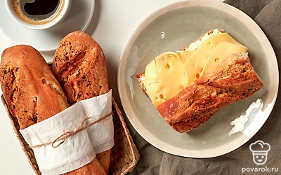 Нарежьте багет с сушеным базиликом ломтиками и натрите их оливковым маслом, сверху положите кусочек сыра.