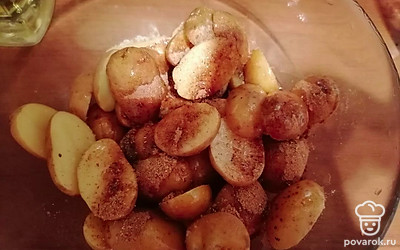 Каждую картофелину разрезать вдоль пополам, выложить в миску, добавить туда растительное масло, соль и специи. 