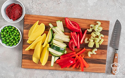 Нарежьте картофель и помидоры дольками, а цукини и перец — брусочками. Измельчите сельдерей небольшими кусочками. Мелко порубите чеснок.