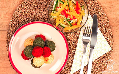 Подавайте цветные сырные шарики на тарелке, выложенной листьями салата. Такая закуска отлично сочетается с овощным салатом.