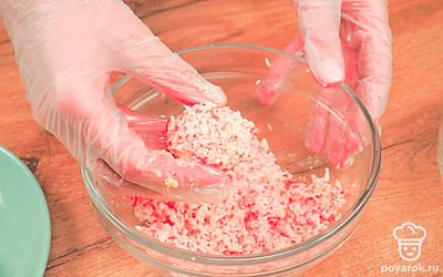 Сделайте шарики. Смешайте в миске тертый сыр, майонез, яйцо, чеснок, соль и перец. Скатайте небольшие шарики. Обваляйте их в натертых крабовых палочках и подайте на стол.