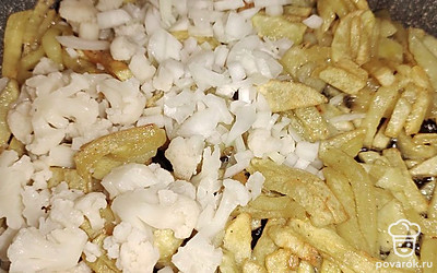 Добавьте нарезанный лук и цветную капусту. Убавьте огонь до средних значений и продолжайте обжаривать еще 5 минут. 