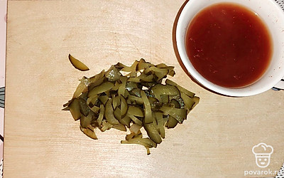 Пока основные ингредиенты томятся в сковороде, нарежьте маринованный огурец тонкой соломкой. Смешайте аджику с кипяченой водой.