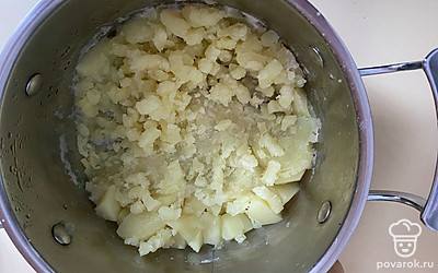 Слейте воду с кастрюли, разомните толкушкой картофель в пюре. 