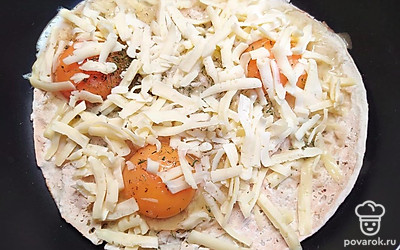 Посолите яйца. Натрите на крупной терке сыр и выложите на яйца. Положите второй лаваш сверху. Жарьте блюдо с двух сторон до готовности яиц.