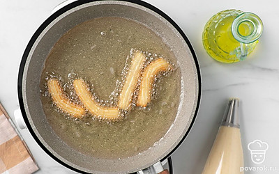 Налейте в глубокую сковороду растительное масло, нагрейте его на сильном огне. Отсадите из кондитерского мешка в горячее масло полоски чуррос длиной около 6-7 см. Жарьте чуррос до золотистого цвета около 3 минут. При помощи шумовки переложите обжаренные чуррос на тарелку с бумажными полотенцами, чтобы избавиться от лишнего масла.