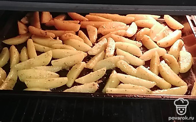 Распределите равномерно картофельные дольки на противне. Поставьте в разогретую до 200 градусов духовку. Запекайте до золотистого цвета.