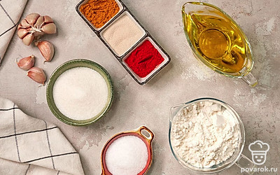 Отмерьте необходимое количество продуктов, удобно расположите их на рабочем столе. Муку просейте через сито. Чеснок очистите от шелухи, мелко нарежьте ножом или пропустите через пресс. Воду подогрейте. Противень застелите пергаментной бумагой и присыпьте мукой.