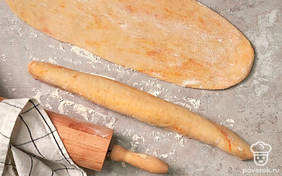 Разделайте тесто. Выложите тесто на рабочую поверхность, предварительно посыпанную небольшим количеством муки. Немного обомните, поделите пополам. Раскатайте в пласты прямоугольной формы. Сверните плотным рулетом, защипните швы. Переложите заготовки на противень.