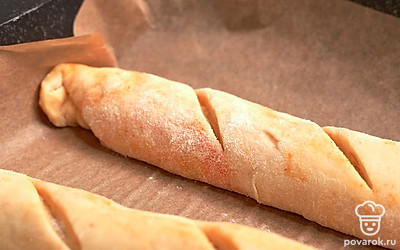 Испеките багеты. Ножом, смазанным маслом, сделайте косые надрезы шириной 3-5 см. Изделие до конца не разрезайте. Каждый отрезок разверните поочередно в разные стороны. Прикройте заготовки полотенцем и поставьте в теплое место на 30 минут. Через полчаса отправьте багеты в духовку, разогретую до 180 градусов, на 10-15 минут.