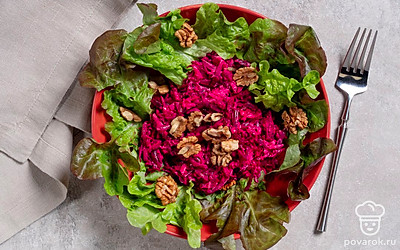 При подаче выложите салат на салатные листья и посыпьте измельченными орехами.