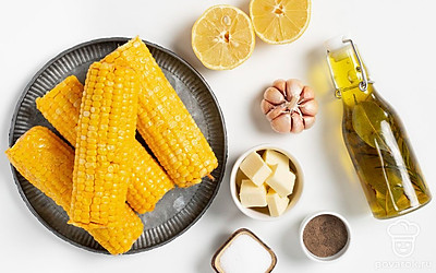 Освободите кукурузу от упаковки, промойте початки. Достаньте из холодильника сливочное масло, чтобы оно размягчилось. Сполосните чеснок, очистите его от шелухи и измельчите. Отделите от стебля листики кинзы, промойте их.