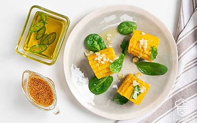 Готовую кукурузу разложите на тарелки и украсьте листиками кинзы.