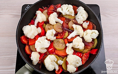 Положите соцветия капусты в сковороду с овощами, аккуратно перемешайте и продолжайте тушить.