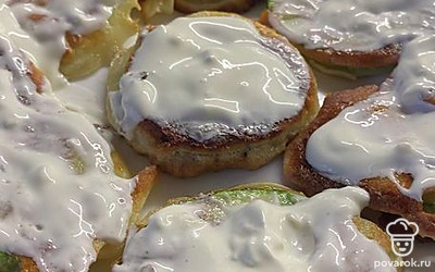 Готовые кабачки выкладываем на тарелку и смазываем чесночным соусом, для приготовления которого, мы смешиваем оставшуюся сметану с чесноком.