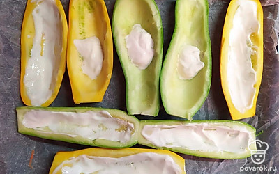 Кабачки разрезаем на две половины и ложкой вынимаем мякоть. Середину каждого кабачка смазываем сметаной.