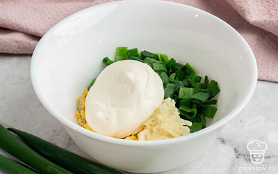 Вареные яйца очистите от скорлупы, разрежьте пополам и извлеките желтки. Натрите на мелкой терке желтки и чеснок. В подходящую емкость выложите желтки, чеснок, майонез и измельченный зеленый лук. Посолите на свой вкус и смешайте до однородности.