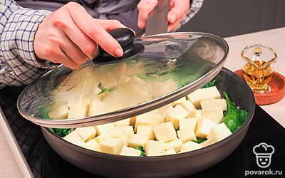 Приготовьте закуску. Разогрейте сковороду. Налейте в нее масло и добавьте лук. Обжаривайте его до образования золотистой корочки. Затем добавьте чеснок и томите еще 2 минуты. Положите к луку и чесноку шпинат, посолите и поперчите, перемешайте. Тушите около 15 минут. Поверх шпината разложите кубики сыра. Накройте крышкой и дождитесь, когда сыр расплавится.