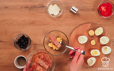 Сделайте начинку. Разрежьте вареные яйца пополам вдоль. Достаньте желтки и положите их в глубокую миску. Один желток отложите, сделайте из него украшение. Тунец добавьте к желткам и измельчите продукты. Добавьте перец по вкусу и майонез, перемешайте.