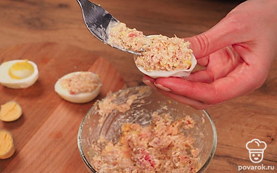 Нафаршируйте яйца. Половинки яиц наполните начинкой. На мелкую терку натрите отложенный желток. Сверху начинку посыпьте тертым желтком.