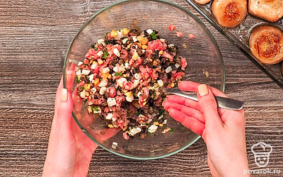 Приготовьте начинку. На том же масле, на котором жарились шляпки, обжарьте 5 минут лук и нарезанные ножки шампиньонов. Переложите их в миску и дайте немного остыть. Смешайте фарш с обжаренным луком и ножками шампиньонов, с зеленью и яйцом. Посолите, поперчите начинку. Хорошо перемешайте.