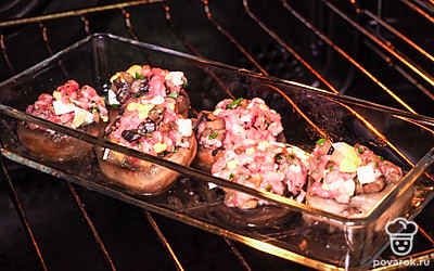 Начините шляпки шампиньонов начинкой. Поставьте пртивень в разогретую до 180℃ духовку на 25 минут.