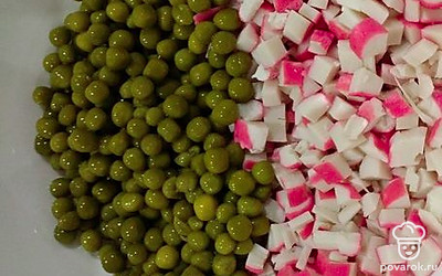 Выложите в миску нарезанные крабовые палочки, добавьте зеленый горошек.