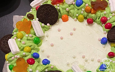 Собранный торт обильно обмажьте другим кремом, это второй вариант со сливочным маслом. Выравнивайте по форме. Оставьте небольшое количество этого крема, около 150 грамм для украшения. Добавьте в него 2 капли пищевого красителя и тщательно перемешайте. 