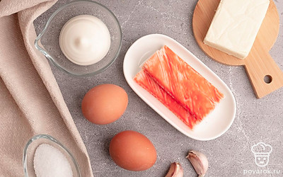 Отварите куриные яйца вкрутую и очистите. Снимите упаковку с крабовых палочек и сырка. Очистите чеснок.