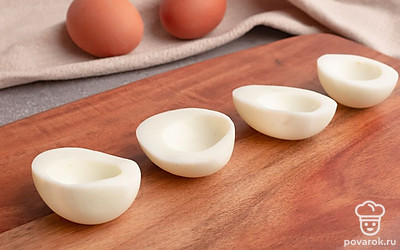 Вареные куриные яйца разрежьте вдоль на две части. Аккуратно выньте желток из каждой половинки. Белки пока отложите в сторону, а желтки разомните вилкой.