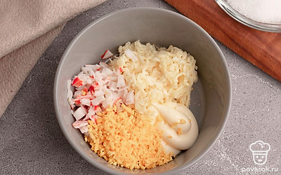 Выложите в миску измельченные крабовые палочки, тертый плавленый сырок и желтки. Добавьте майонез, выдавите зубчик чеснока. Все перемешайте. Посолите начинку по вкусу.