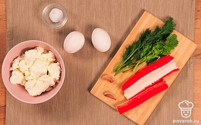 Крабовые палочки положите размораживаться на нижнюю полку холодильника. Яйца отварите вкрутую (приблизительное время варки 10 минут с момента закипания), остудите и очистите. Свежие яйца очистить проще, если после варки разбить скорлупу в нескольких местах, а затем погрузить их на некоторое время в холодную воду. Приготовьте пищевую пленку или целлофановый пакет. Удобно разложите на столе нужные продукты.